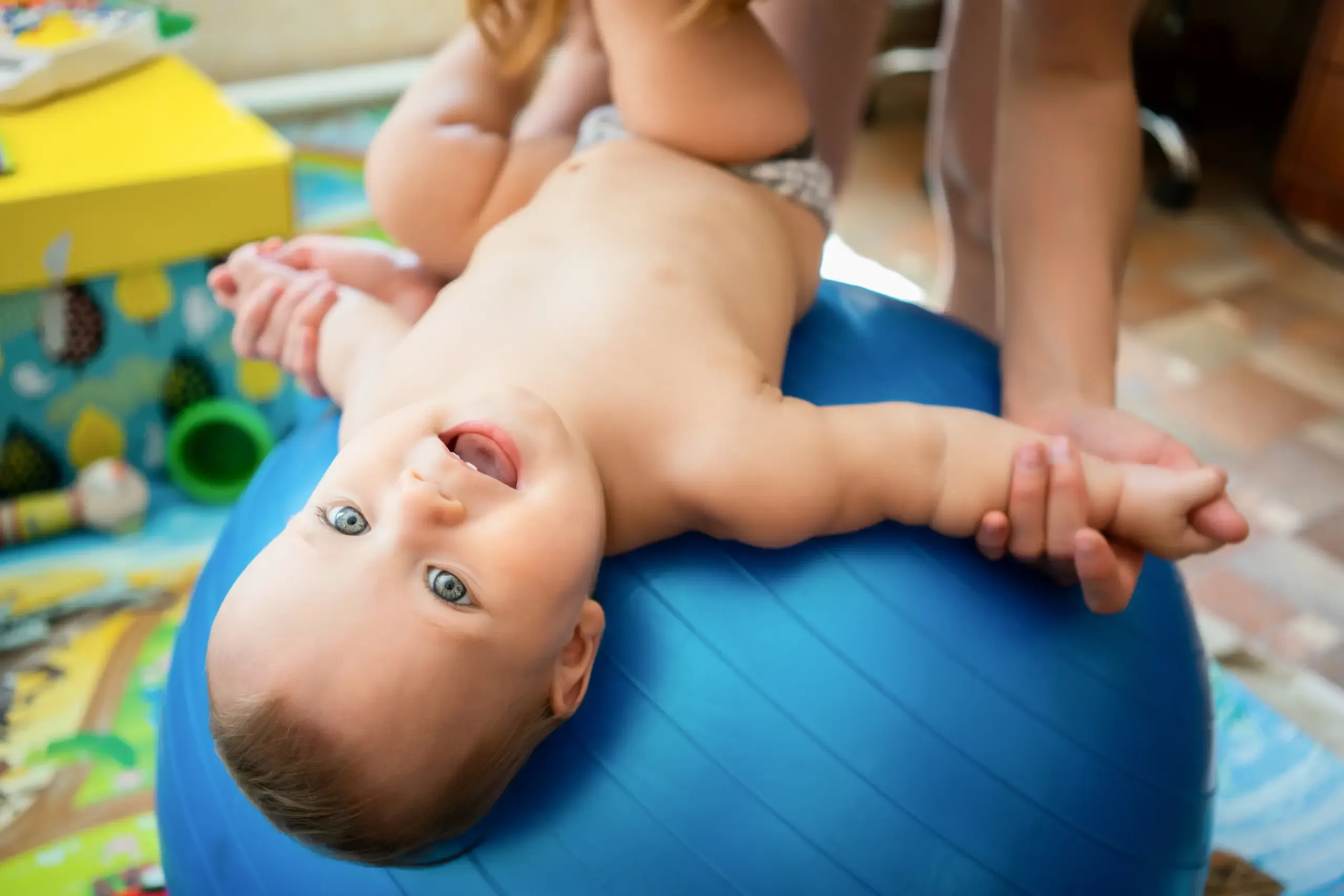 Baby liegt lachend auf einem Gymnastikball