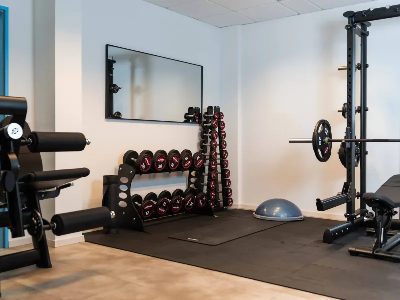 Trainingsfläche bei Physio Karakurt mit Kurzhanteln, Power Rack und Hantelbank