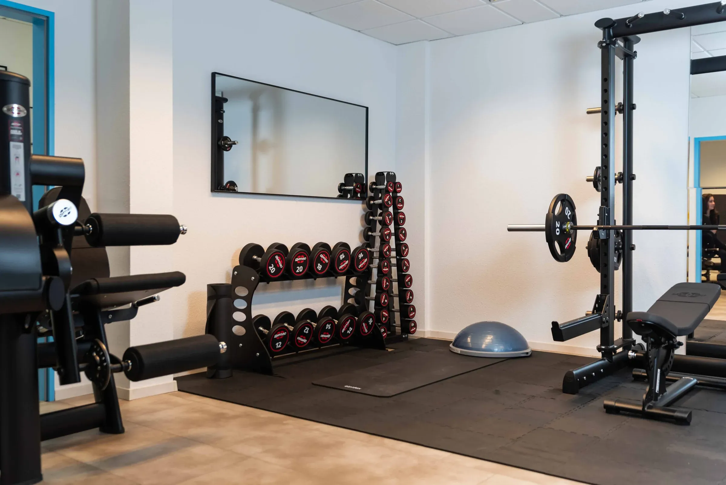 Trainingsfläche bei Physio Karakurt mit Kurzhanteln, Power Rack und Hantelbank