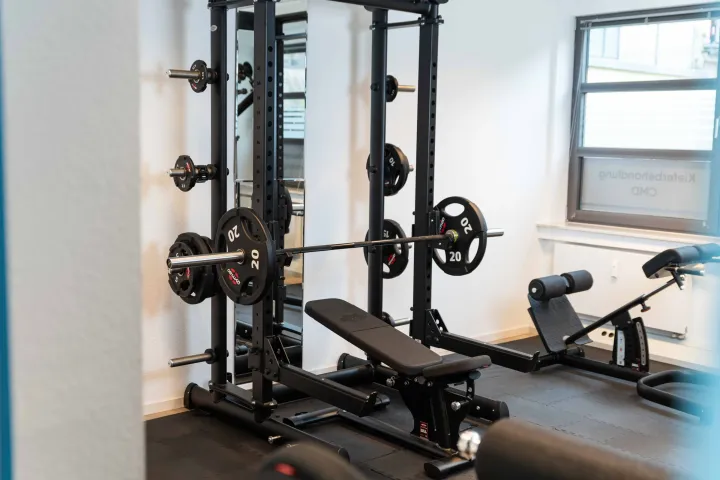 Power Rack mit Langhantel und Hantelbank auf der Trainingsfläche