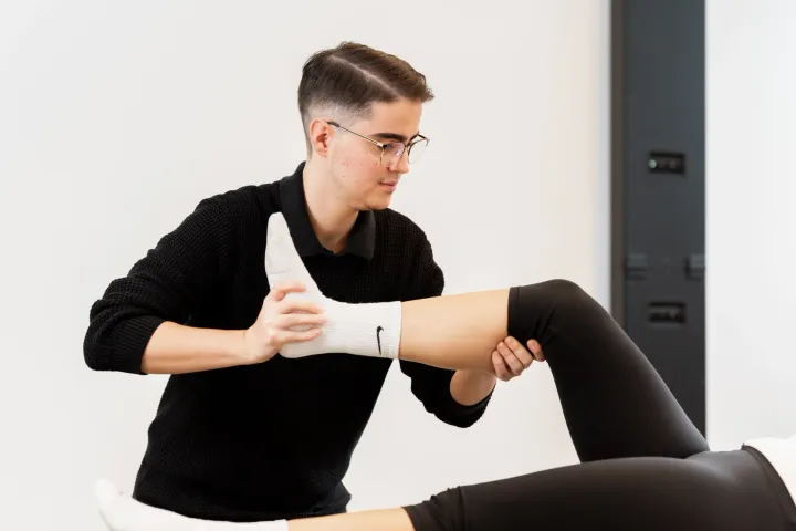 Therapeut führt das Bein einer Patientin in einem PNF-Muster